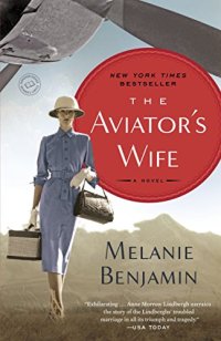 the Aviator's Wife by Melanie Benjamin (cover) Image: a woman wearing a hat and in a blue dress (holding a purse and a travel bag) walks beneath the propeller of a small aircraft